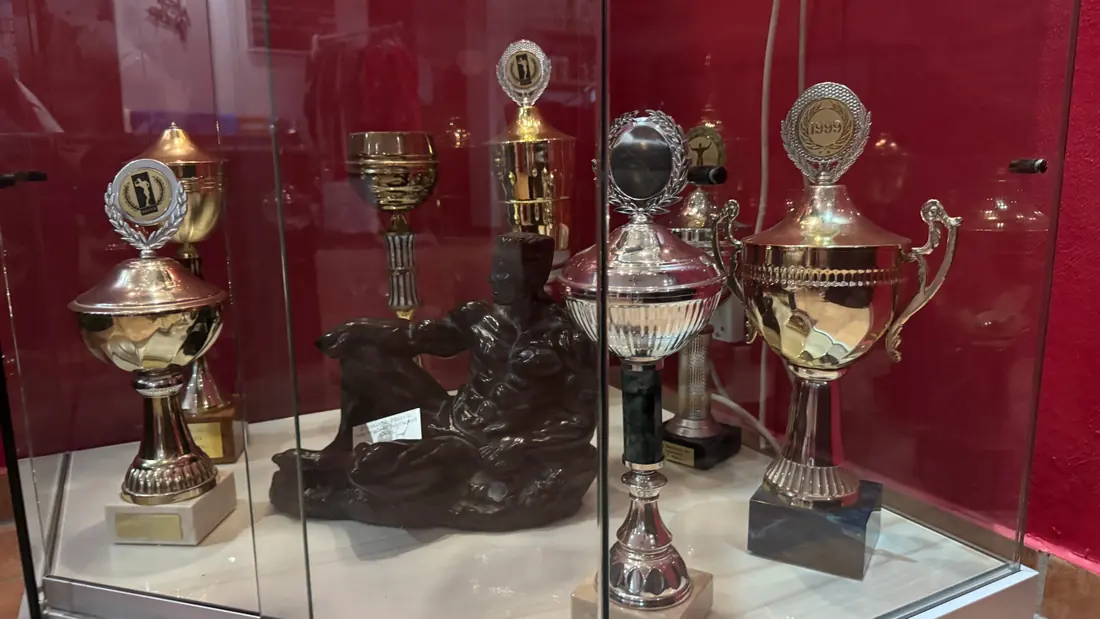 Blick in die Pokalvitrine mit Bronzefigur und Wettkampfpokalen